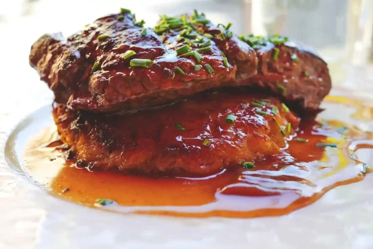 Perfectly cooked NY strip steak in oven with crispy crust and juicy pink center, resting on a cast iron skillet with fresh herbs. Step-by-step guide for how to cook NY strip steak in oven.